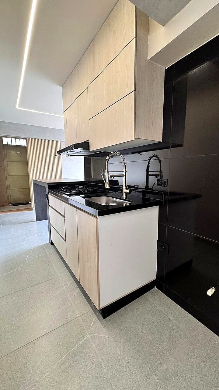 Light-wood kitchen with black countertop in the Rosales apartment
